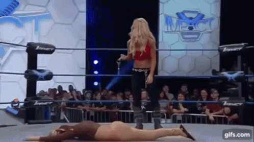 A Woman In A Red Top Is Standing Next To A Woman Laying On The Ground . GIF