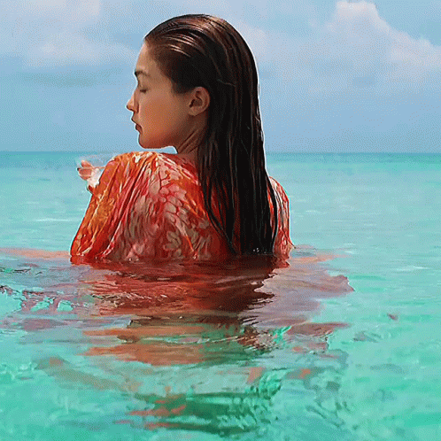 A Woman In A Red Top Is Swimming In The Ocean GIF
