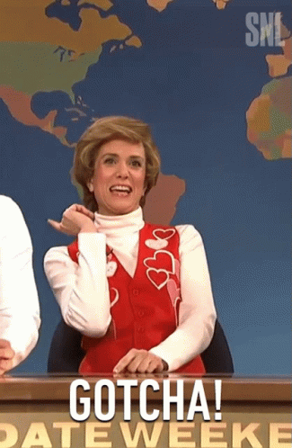 A Woman In A Red Vest Is Sitting At A Desk With The Words Gotcha On It GIF