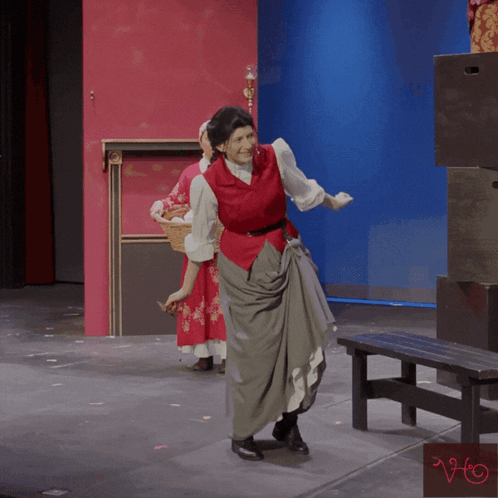 A Woman In A Red Vest Stands On A Stage GIF
