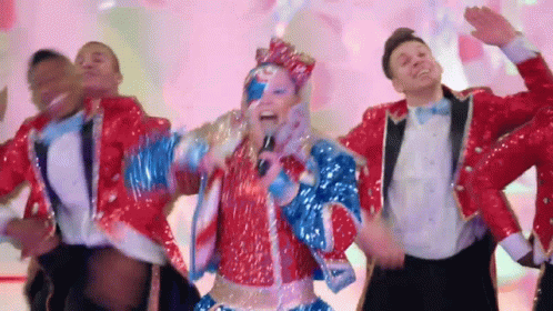 A Woman In A Red White And Blue Outfit Sings Into A Microphone GIF