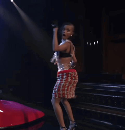 A Woman In A Red White And Blue Skirt Is Dancing In A Dark Room GIF