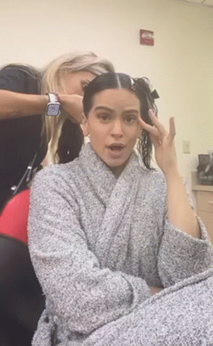 A Woman In A Robe Is Getting Her Hair Done By A Hairdresser GIF