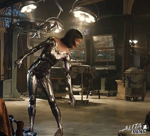 A Woman In A Robotic Suit Is In An Operating Room With The Word Alita Army On The Bottom Right GIF