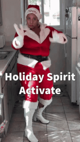 A Woman In A Santa Costume Is Dancing In A Kitchen GIF