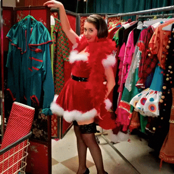A Woman In A Santa Costume Is Standing In Front Of A Closet Full Of Clothes GIF