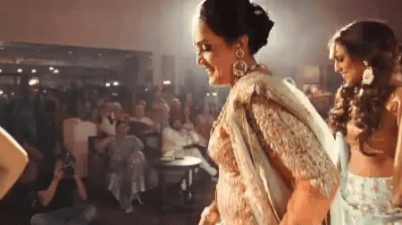 A Woman In A Sari Is Dancing In Front Of A Crowd Of People . GIF