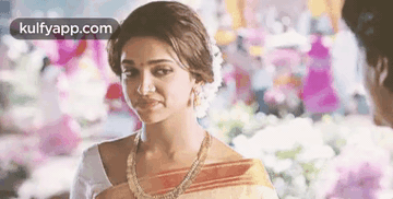 A Woman In A Sari Is Standing Next To A Man In A Room And Smiling . GIF