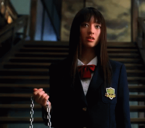 A Woman In A School Uniform Is Standing In Front Of Stairs . GIF