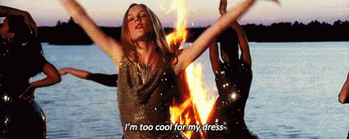 A Woman In A Sequined Dress Is Standing In Front Of A Fire And Says I 'M Too Cool For My Dress GIF