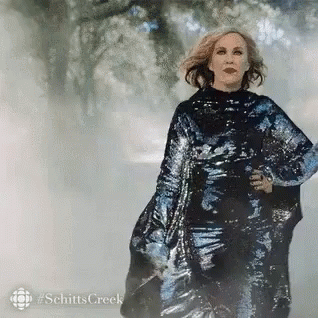 A Woman In A Sequined Dress Is Walking In The Fog . GIF