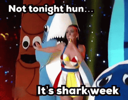 A Woman In A Shark Costume Is Singing Into A Microphone .. GIF