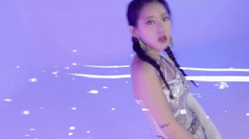 A Woman In A Silver Dress Is Standing In A Purple Room . GIF