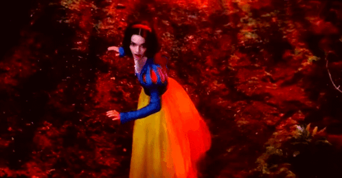 A Woman In A Snow White Costume Is Standing In A Red Forest . GIF