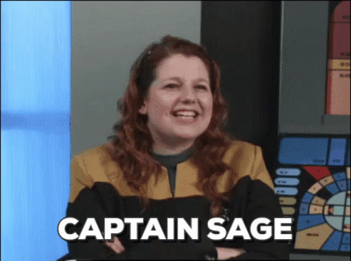A Woman In A Star Trek Uniform Is Smiling With The Words Captain Sage Above Her GIF