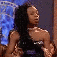 A Woman In A Strapless Black Dress Is Sitting On A Couch With Her Eyes Closed . GIF