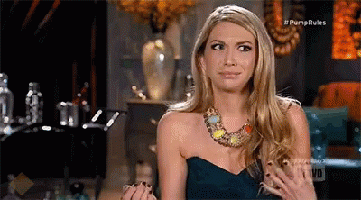 A Woman In A Strapless Dress And Necklace Is Sitting On A Couch . GIF
