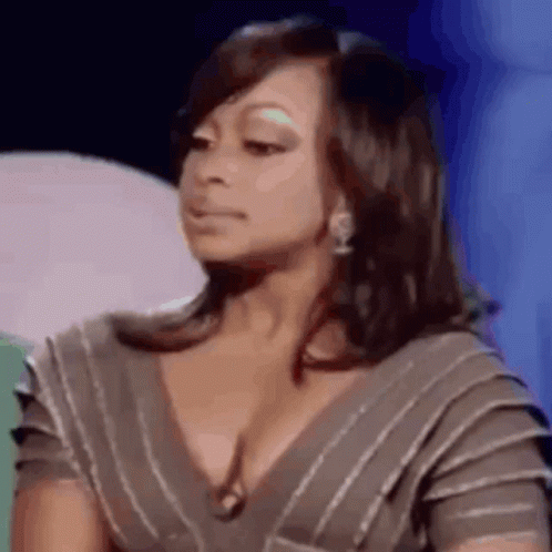 A Woman In A Striped Dress Is Making A Funny Face While Sitting On A Stage . GIF