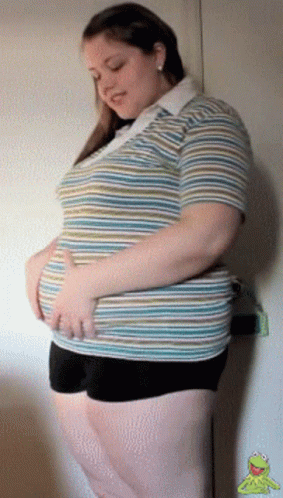 A Woman In A Striped Shirt And Black Shorts Holds Her Stomach GIF