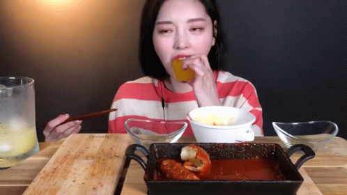 A Woman In A Striped Shirt Is Eating Food From A Bowl GIF
