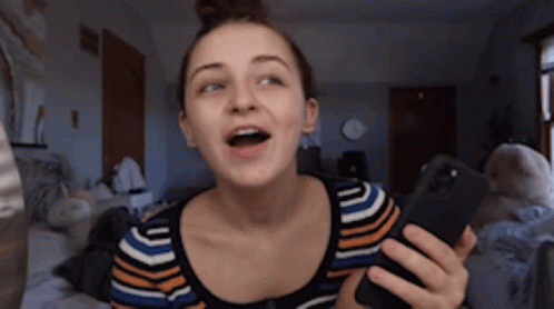 A Woman In A Striped Shirt Is Holding A Cell Phone GIF