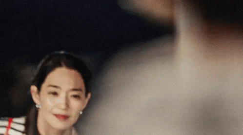 A Woman In A Striped Shirt Is Looking At A Man In A White Shirt . GIF