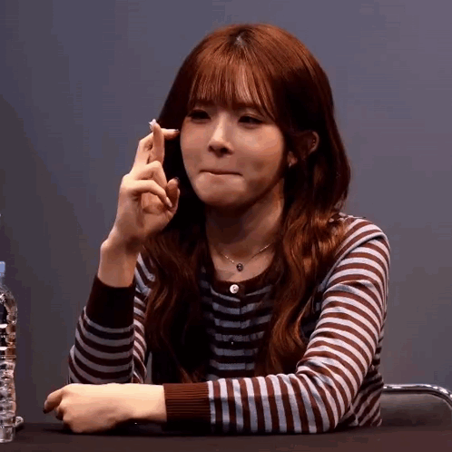 A Woman In A Striped Shirt Is Making A Funny Face GIF