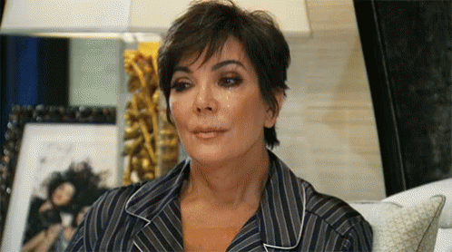 A Woman In A Striped Shirt Is Sitting On A Couch With Her Eyes Closed And Tears Running Down Her Face . GIF