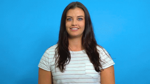 A Woman In A Striped Shirt Is Smiling While Holding A Cardboard Trophy GIF