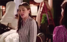 A Woman In A Striped Shirt Is Standing Next To Another Woman In A Pink Shirt . GIF