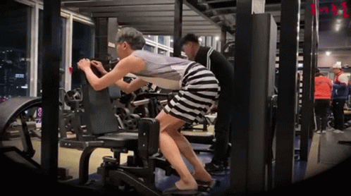 A Woman In A Striped Skirt Is Doing Exercises In A Gym GIF