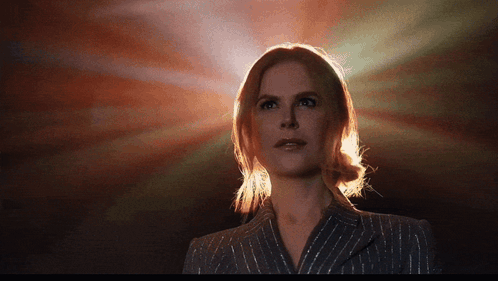 A Woman In A Striped Suit Is Standing In Front Of A Red Background GIF