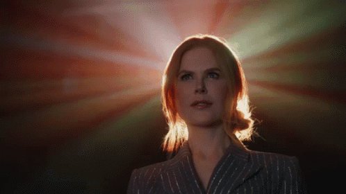 A Woman In A Striped Suit Stands In Front Of A Red Light GIF