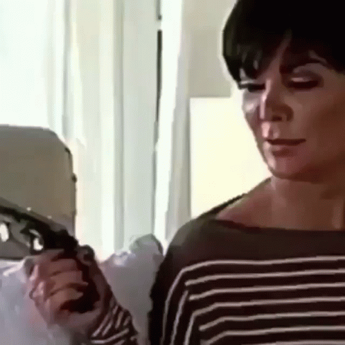 A Woman In A Striped Sweater Is Holding A Gun In Her Hand . GIF