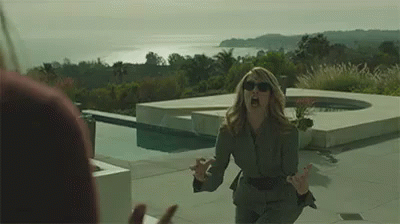 A Woman In A Suit And Sunglasses Is Screaming At A Man In Front Of A Pool . GIF