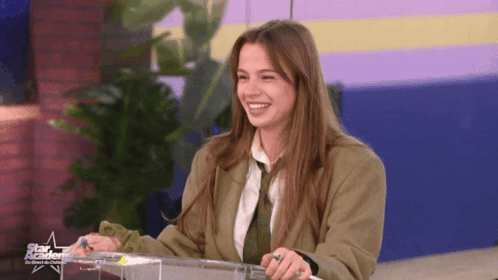 Woman In Suit And Tie Smiling In Front Of Star Academy Sign GIF