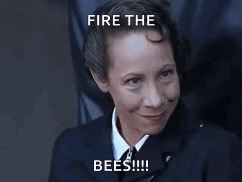 A Woman In A Suit And Tie Is Smiling With The Words `` Fire The Bees '' Written Above Her . GIF