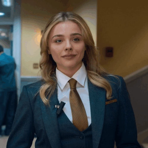 A Woman In A Suit And Tie With A Name Tag That Says ' Amanda ' GIF