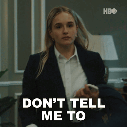 A Woman In A Suit And White Shirt Is Holding A Cell Phone And Says " Don 'T Tell Me To " GIF