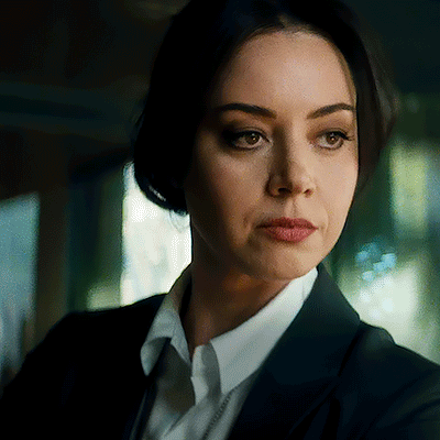 A Woman In A Suit And White Shirt Is Looking At The Camera With A Serious Look On Her Face . GIF