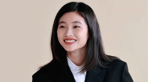 A Woman In A Suit And White Shirt Is Smiling . GIF