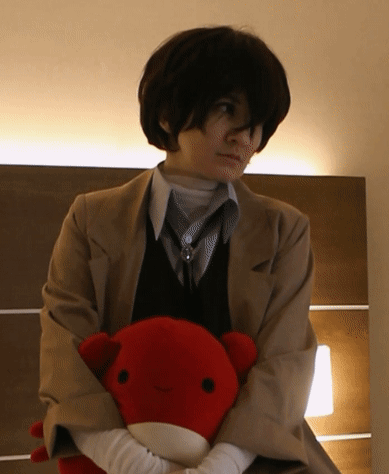 A Woman In A Suit Holds A Stuffed Animal In Her Hands GIF