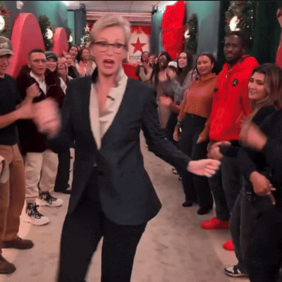 a woman in a suit is dancing in front of a macys sign