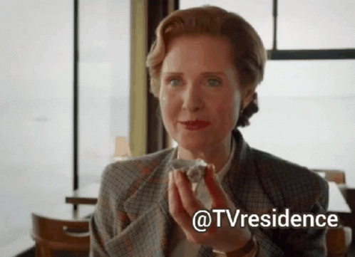 A Woman In A Suit Is Holding A Piece Of Cake In Her Hands . GIF