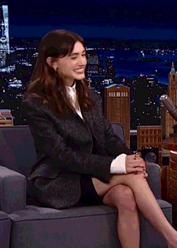 A Woman In A Suit Is Sitting In A Chair With Her Legs Crossed . GIF