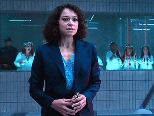 Woman In Suit Standing In Front Of Women In White Dresses GIF