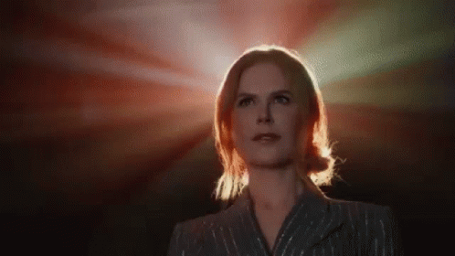 A Woman In A Suit Is Standing In Front Of A Red Light And Looking Up . GIF