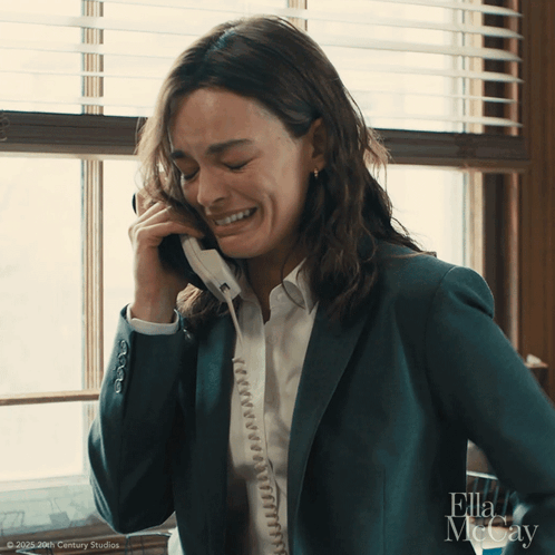 A Woman In A Suit Is Talking On A Phone With Ella Mccay Written On The Bottom GIF