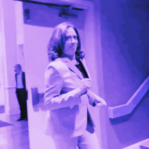 A Woman In A Suit Is Walking Down A Staircase GIF