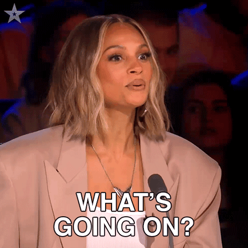 A Woman In A Suit Says What 'S Going On In Front Of A Microphone GIF